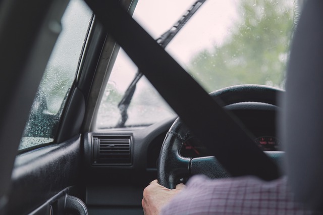 Muž sedí za volantom auta, je pripútaný bezpečnostným pásom a šoféruje